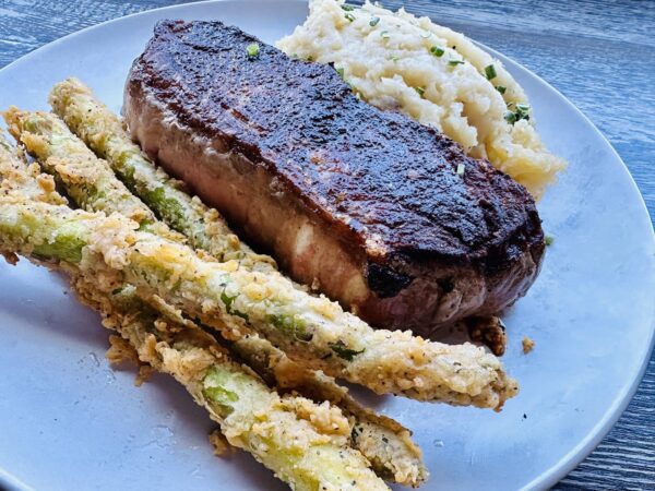 MOCO Blackened Steak with mashed potatoes and asparagus.