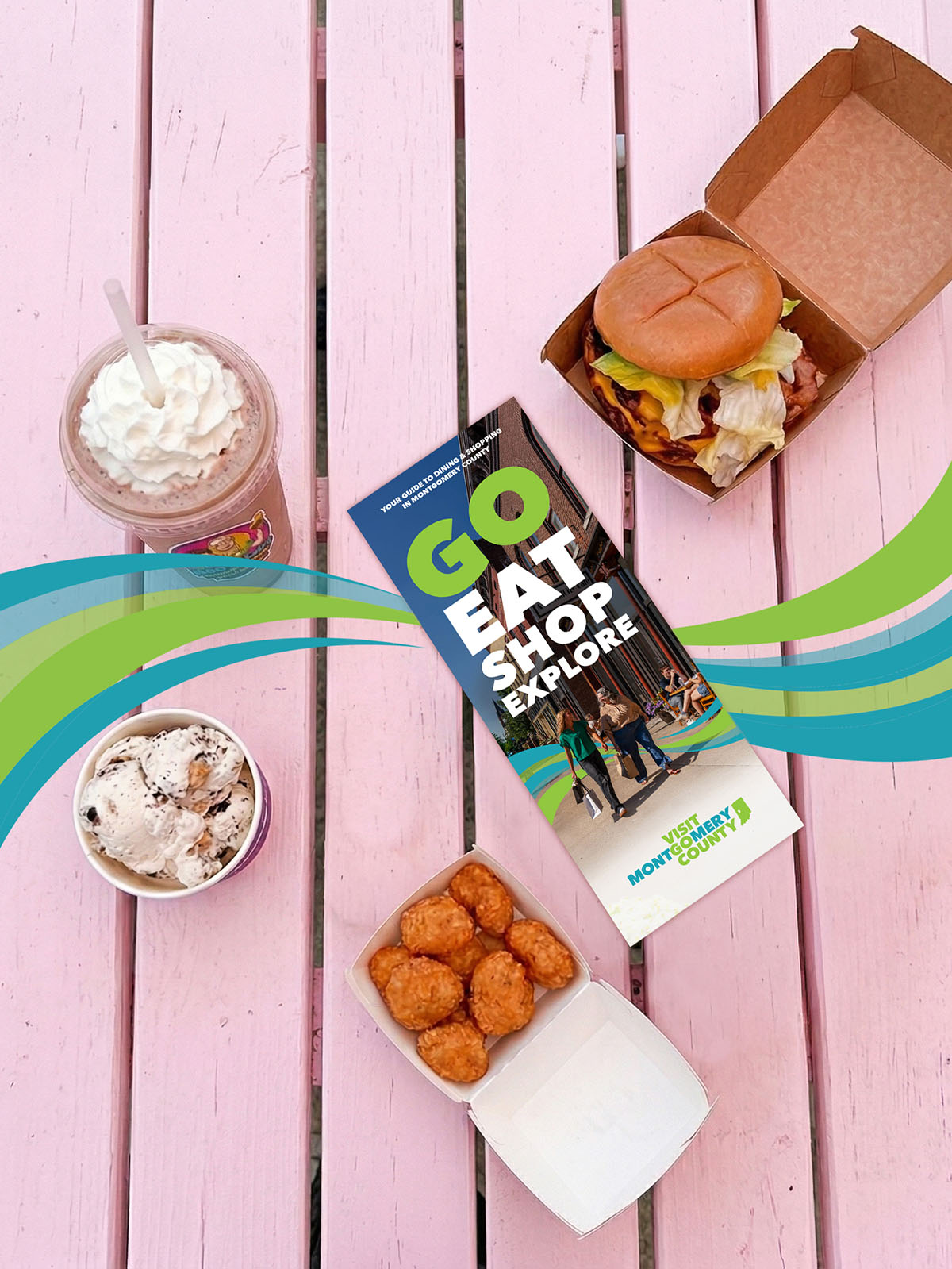 A cheeseburger, hash rounds, milk shake, and a cup with ice cream sitting on an outdoor table