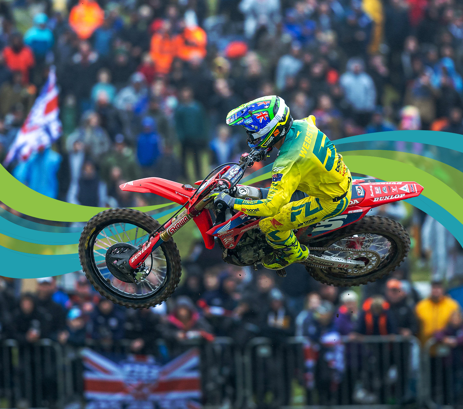 Motorcross athlete performing a jump on his bike in mid-air while crowd watches