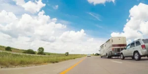 Midwest farmland is to the left, with a state road with an RV driving is to the right